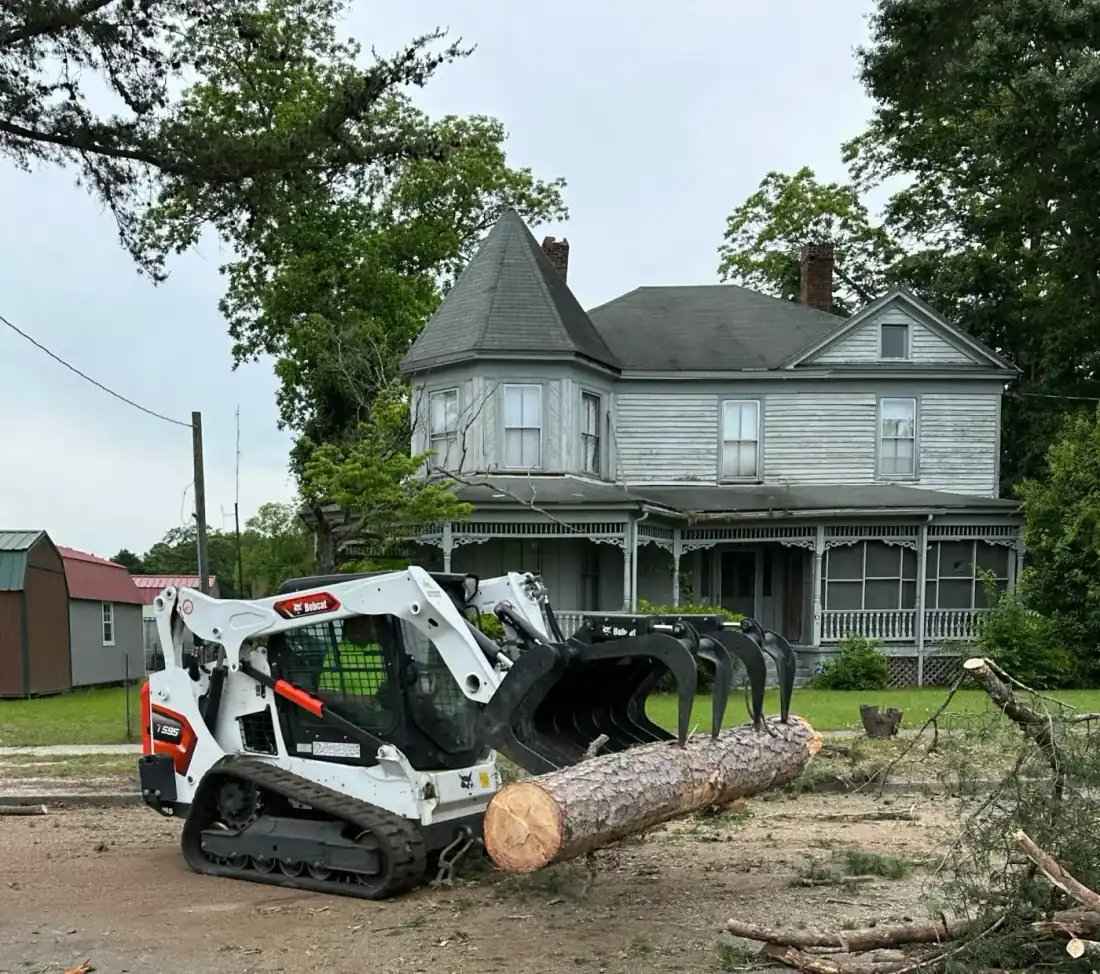Bobcat moving logs at residential job site in Clayton