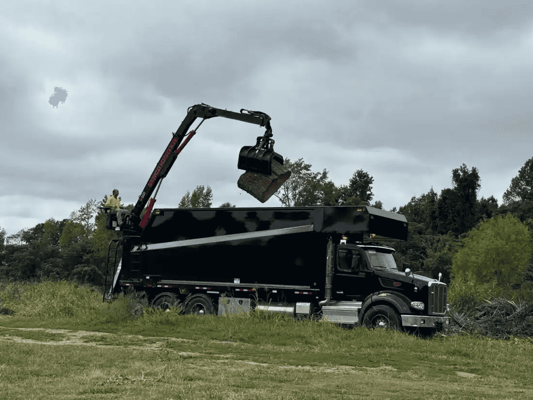 Peterbilt grapple truck loading tree debris at job site