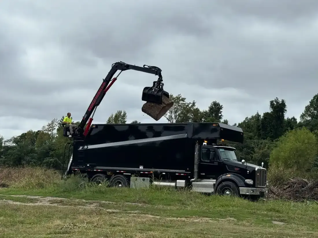 Peterbilt grapple truck loading tree debris with hydraulic claw at Eastern NC job site