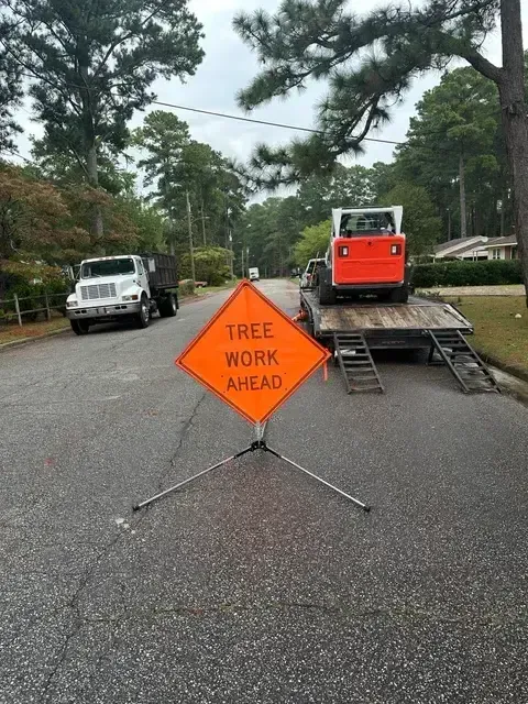 Tree Work Ahead warning sign with wood chipper on residential street